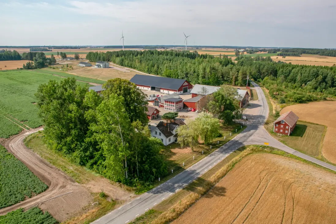 En flygbild över Torpa Gård som visar flera röda hus och en del träd.